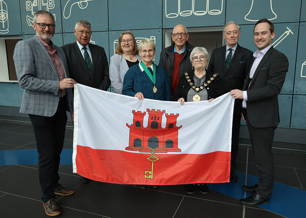 Raising the flag for Gibraltar are, from left, Alderman William McGaughey, Commodore Richard Lord, Alderman Maureen Morrow, High Sheriff Mrs. Patricia Perry, Cllr. Jackson Minford, Mayor Alderman Beth Adger MBE, Julian Lyne-Pirkis, and Jonathan McGrandle,